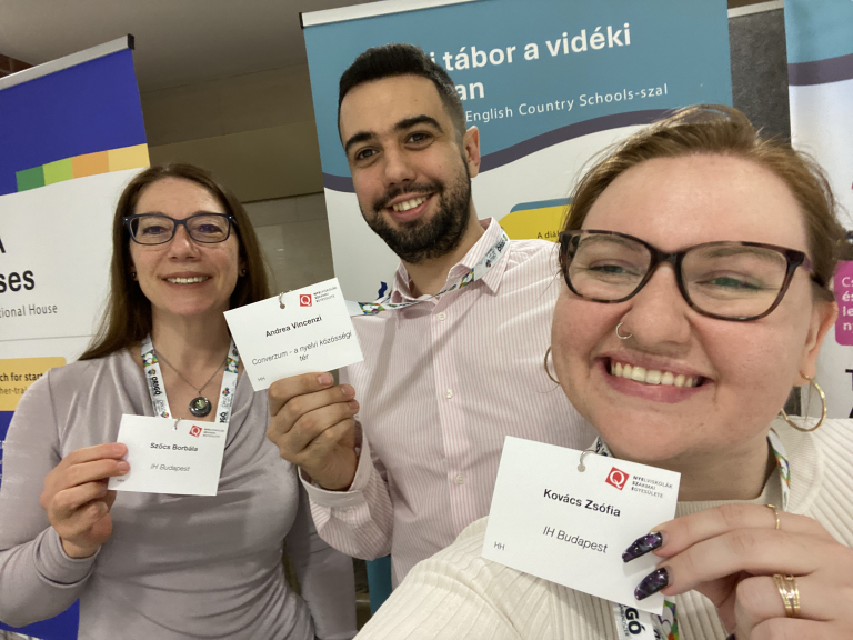 Language school representatives smile with event badges at a Budapest education fair.